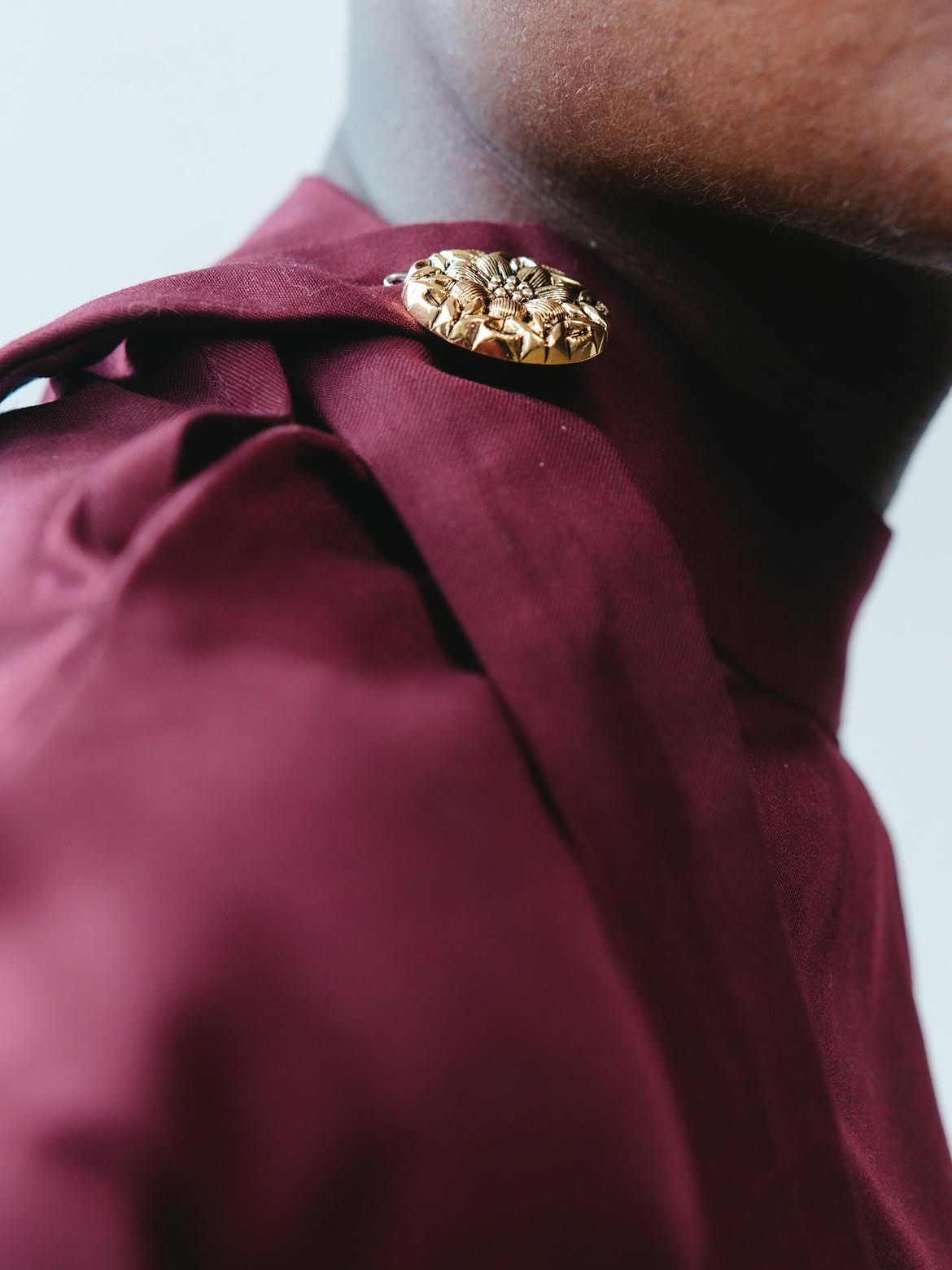 Study VI: Macro close-up on the handcrafted floral gold brooch & structured collar fold